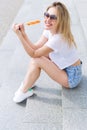 Beautiful young cheerful happy girl eating ice cream , smiling in shorts and a white T-shirt on the area on a bright sunny day Royalty Free Stock Photo