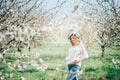 Beautiful young cheerful pregnant woman in wreath of flowers on head touching belly while walking in spring tree garden. Beauty Royalty Free Stock Photo