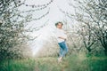 Beautiful young cheerful pregnant woman in wreath of flowers on head touching belly while walking in spring tree garden. Beauty Royalty Free Stock Photo