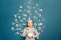 Beautiful young child girl with flying money on blue background Royalty Free Stock Photo