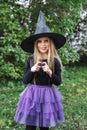 Beautiful young child girl in witch costume outdoors. Happy Halloween Royalty Free Stock Photo