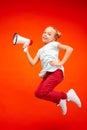 Beautiful young child teen girl jumping with megaphone isolated over red background Royalty Free Stock Photo