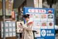 A beautiful young Chinese lady using her cell phones while walking into a shopping mall. Telecome technology conecept