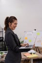 Beautiful young concentration business woman using laptop while standing in office