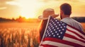 Beautiful young couple with american flag on wheat field at sunset Royalty Free Stock Photo