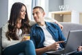 Beautiful young couple bonding to each other using laptop while sitting on the couch together. Royalty Free Stock Photo