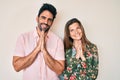 Beautiful young couple of boyfriend and girlfriend together praying with hands together asking for forgiveness smiling confident