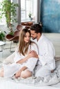 Beautiful young couple celebrating Saint Valentine`s Day, spending romantic time together at home, wearing white bathrobes and Royalty Free Stock Photo