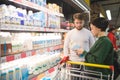 A beautiful young couple chooses dairy products in a supermarket. The girl reads the milk ethics in the store Royalty Free Stock Photo