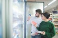 A beautiful young couple chooses frozen foods near the refrigerator in a supermarket Royalty Free Stock Photo
