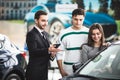 Beautiful young couple choosing a car at the dealership talking to the salon manager with tablet in hands Royalty Free Stock Photo