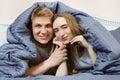 Beautiful young couple cuddling in bed under the covers Royalty Free Stock Photo