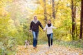 Beautiful young couple with dog running in autumn forest Royalty Free Stock Photo