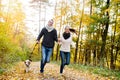 Beautiful young couple with dog running in autumn forest Royalty Free Stock Photo