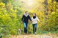 Beautiful young couple with dog running in autumn forest Royalty Free Stock Photo