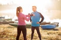 Wide aspect ratio photo of beautiful young couple exercising and stretching by the river or lake Royalty Free Stock Photo