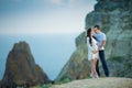 Beautiful young couple expecting baby posing on mountain view with blue sea as background Royalty Free Stock Photo