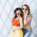 Beautiful young couple fashionable girls blonde and brunette in a bright yellow dress and sunglasses posing and smiling for the ca Royalty Free Stock Photo