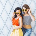 Beautiful young couple fashionable girls blonde and brunette in a bright yellow dress and sunglasses posing and smiling for the ca
