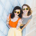 Beautiful young couple fashionable girls blonde and brunette in a bright yellow dress and sunglasses posing and smiling for the ca Royalty Free Stock Photo