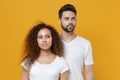 Beautiful young couple friends european guy african american girl in white t-shirts posing isolated on yellow wall Royalty Free Stock Photo