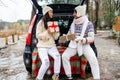 Young couple giving presents and looking each other sitting in the trunk in winter holidays. Royalty Free Stock Photo