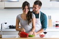 Beautiful young couple having romantic moments, hugging and cutting vegetables in the kitchen at home. Royalty Free Stock Photo