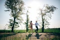 Beautiful young couple holding hands and running in sunshine in spring field and trees. Silhouettes of happy family having fun in Royalty Free Stock Photo