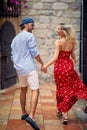 Beautiful young couple holding hands and running together. Beautiful woman in red summer dress, stylish handsome man. Date, Royalty Free Stock Photo