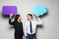 Beautiful young couple is holding speech bubbles, looking at camera and smiling, on gray background Royalty Free Stock Photo