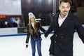 Beautiful young couple ice skating on rink outdoors.