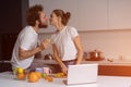 Beautiful young couple kissing feeding each other making fun at modern kitchen and smiling while cooking at home. Pretty Royalty Free Stock Photo