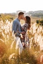 Beautiful young couple kissing in a field with grass at sunset. stylish man and woman having fun outdoors. family concept. copy Royalty Free Stock Photo