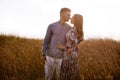 Beautiful young couple kissing in a field with grass at sunset. stylish man and woman having fun outdoors. family day concept. Royalty Free Stock Photo