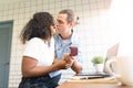 Beautiful young couple kissing at the home office and enjoy your time together with a red gift box for wedding rings, man makes a Royalty Free Stock Photo