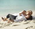 Beautiful young couple kissing on sunset lying on sand, sunset t