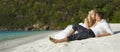 Beautiful young couple kissing on sunset lying on sand, sunset t