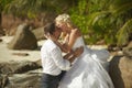 Beautiful young couple kissing on sunset, standing barefoot on b