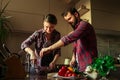 Beautiful young couple in kitchen at home while cooking healthy food. Wife mix salad. Husband salting salad. Scene from family Royalty Free Stock Photo