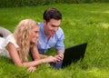 Beautiful, young couple with laptop in the grass