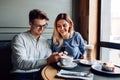 Young couple in headphone, using a smartphone, spending time at cafe Royalty Free Stock Photo