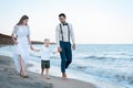 Beautiful Young couple with little boy walks on the beach. Parents keep son`s hands Royalty Free Stock Photo