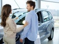 Beautiful young couple looking a new car at the dealership showroom. Royalty Free Stock Photo