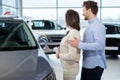 Beautiful young couple looking a new car at the dealership showroom. Royalty Free Stock Photo