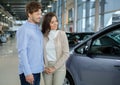 Beautiful young couple looking a new car at the dealership showroom. Royalty Free Stock Photo