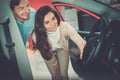 Beautiful young couple looking a new car at the dealership showroom. Royalty Free Stock Photo