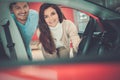 Beautiful young couple looking a new car at the dealership showroom. Royalty Free Stock Photo