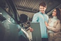 Beautiful young couple looking a new car at the dealership showroom. Royalty Free Stock Photo