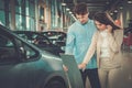 Beautiful young couple looking a new car at the dealership showroom. Royalty Free Stock Photo