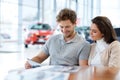 Beautiful young couple looking a new car at the dealership showroom. Royalty Free Stock Photo